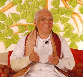 Grand Master Choa Kok Sui seated in white robes, smiling, holding a book